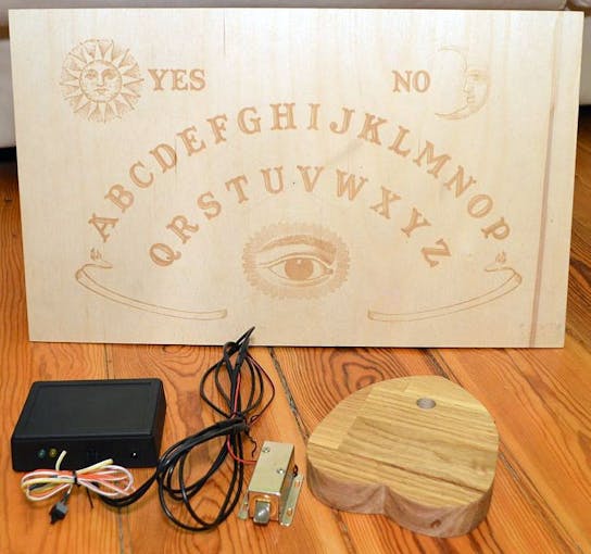 The complete system: the receiver, with an electronic lock and (not pictured) wires for charging the planchette, and the planchette itself. On the back of the board the RFID tags are placed.