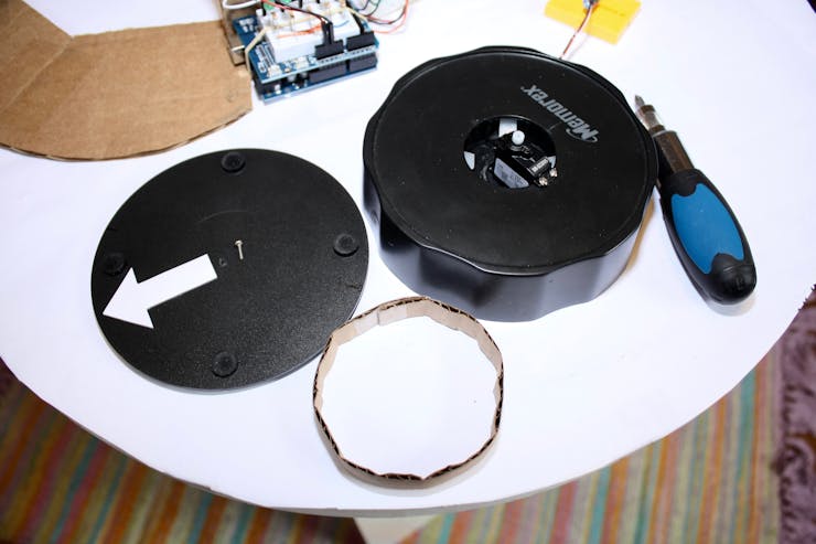 The servo motor is attached to the CD labeler base, and the bottom piece is reused as the surface to sit the camera. The circular cardboard is added between the two pieces for stability.